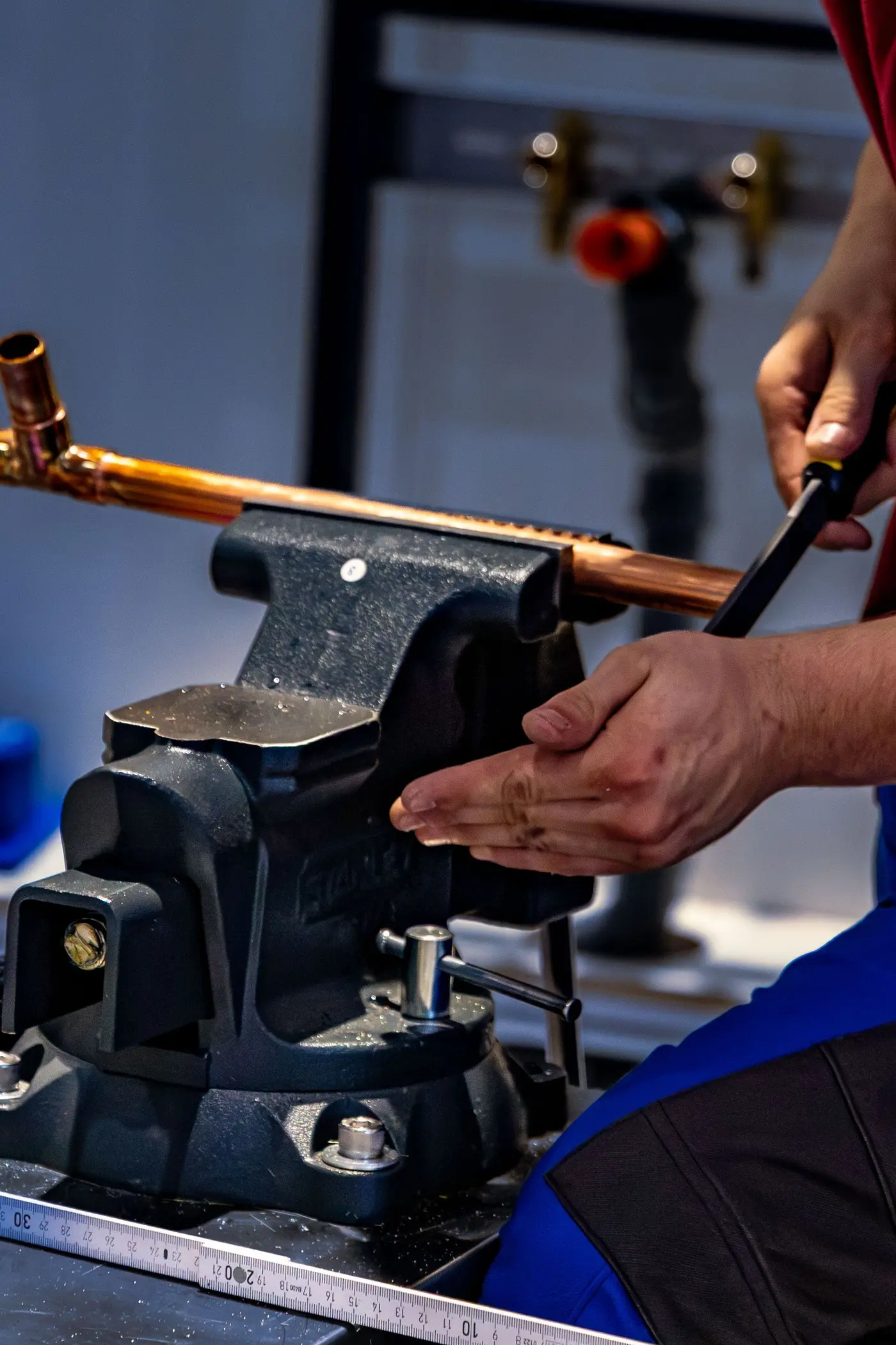 Plumber bending a copper pipe held in a bench vice