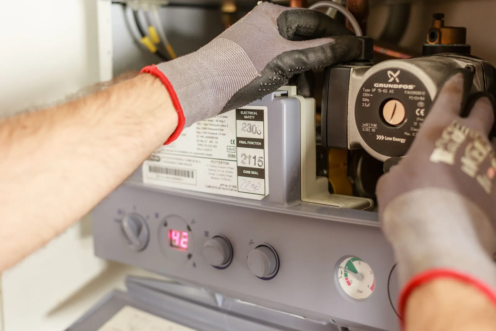 Plumber in work gloves repairing a water heater pump